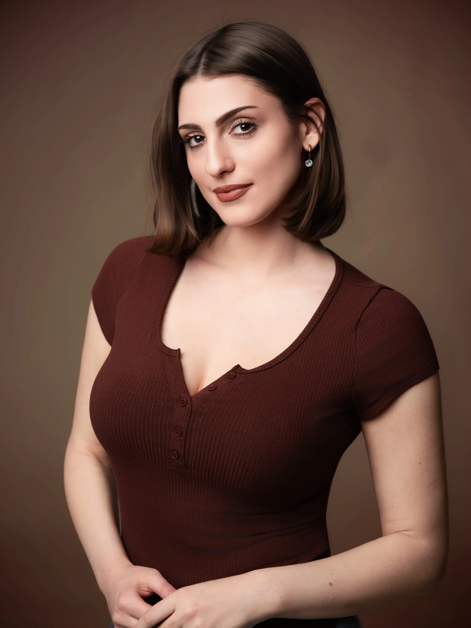Woman with a dark bob in a brown top against a brown backdrop