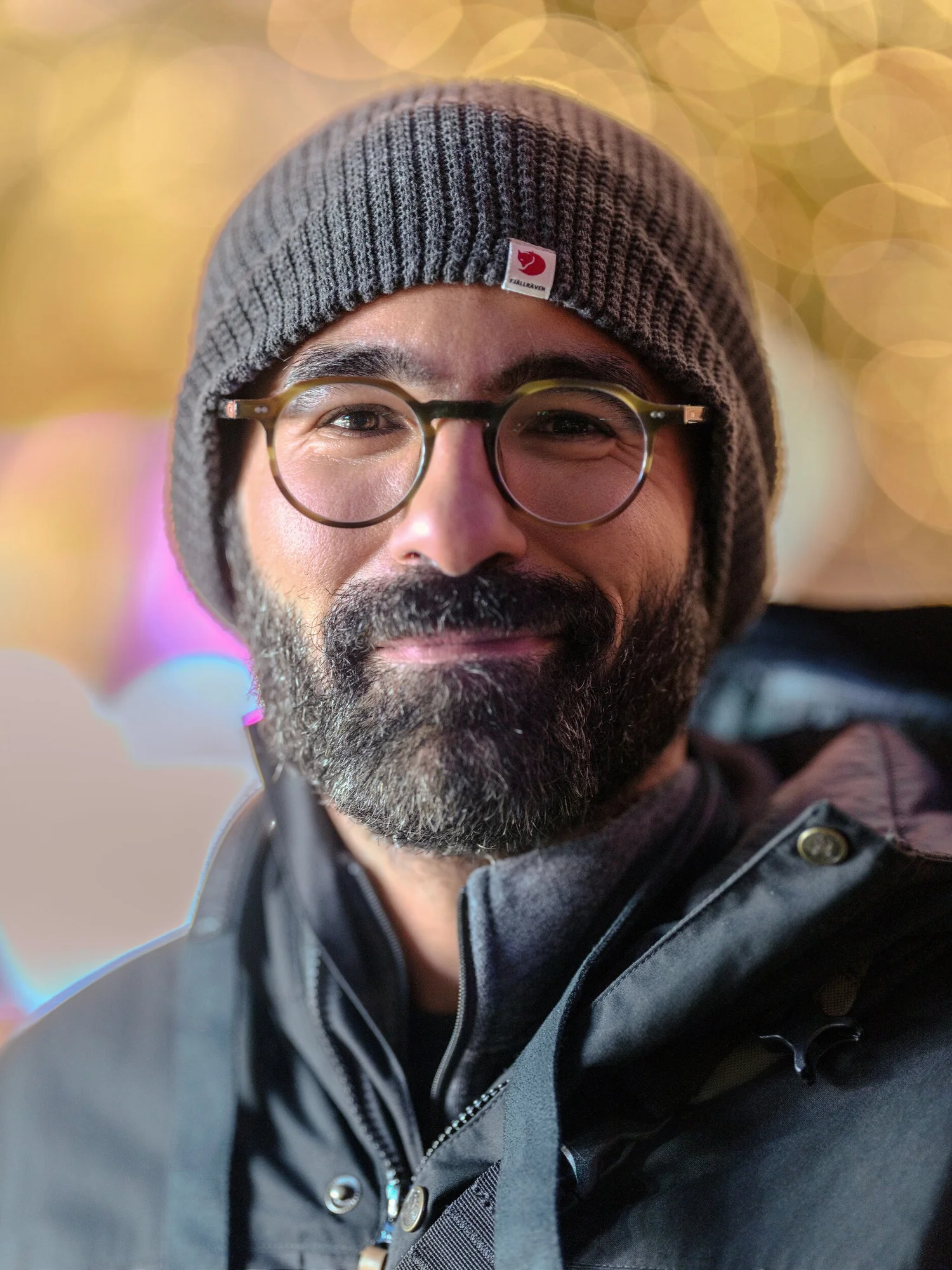 Participant in glasses and a beanie against soft holiday-light bokeh