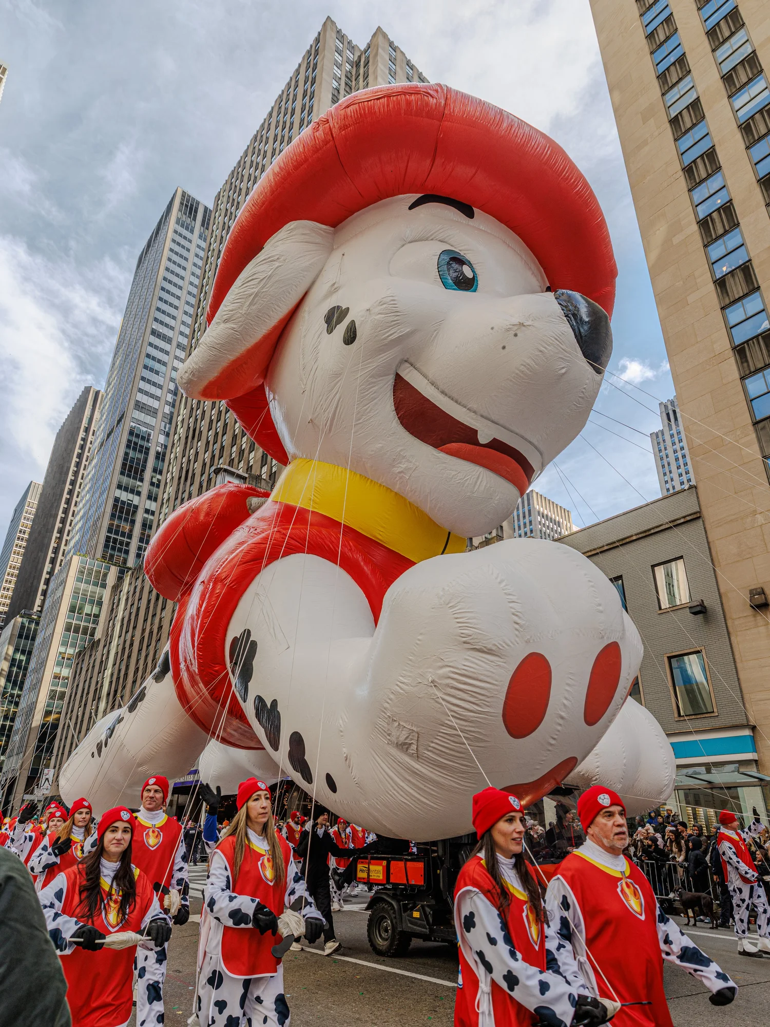 Giant cartoon dog balloon in a firefighter’s hat between buildings
