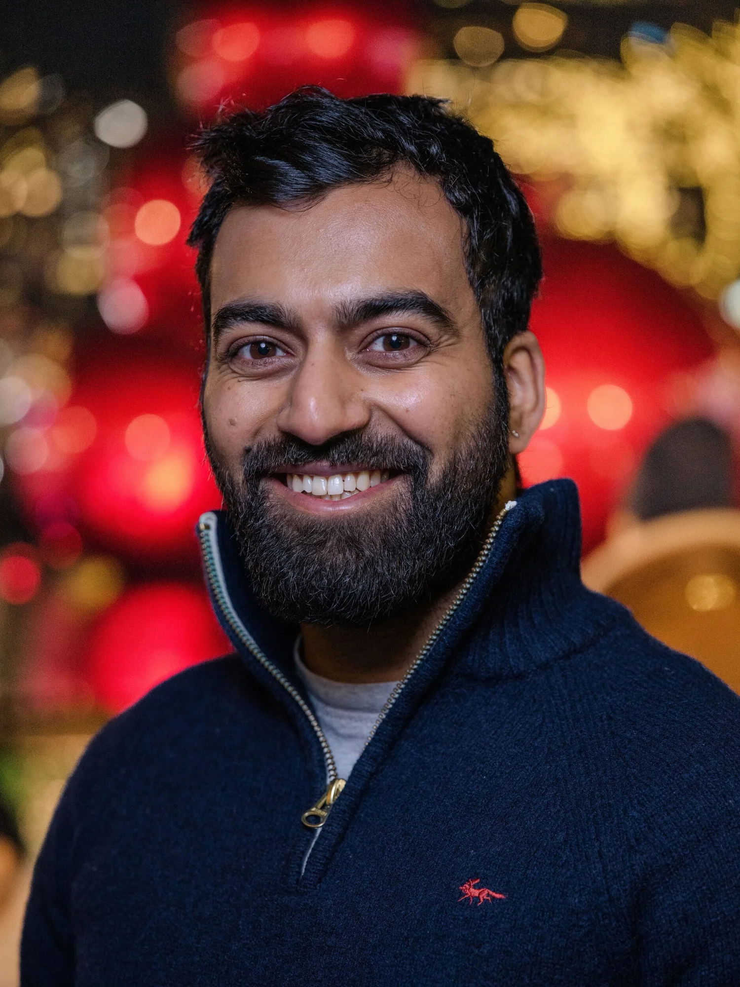 Smiling workshop participant in front of giant red ornaments on Fifth Avenue