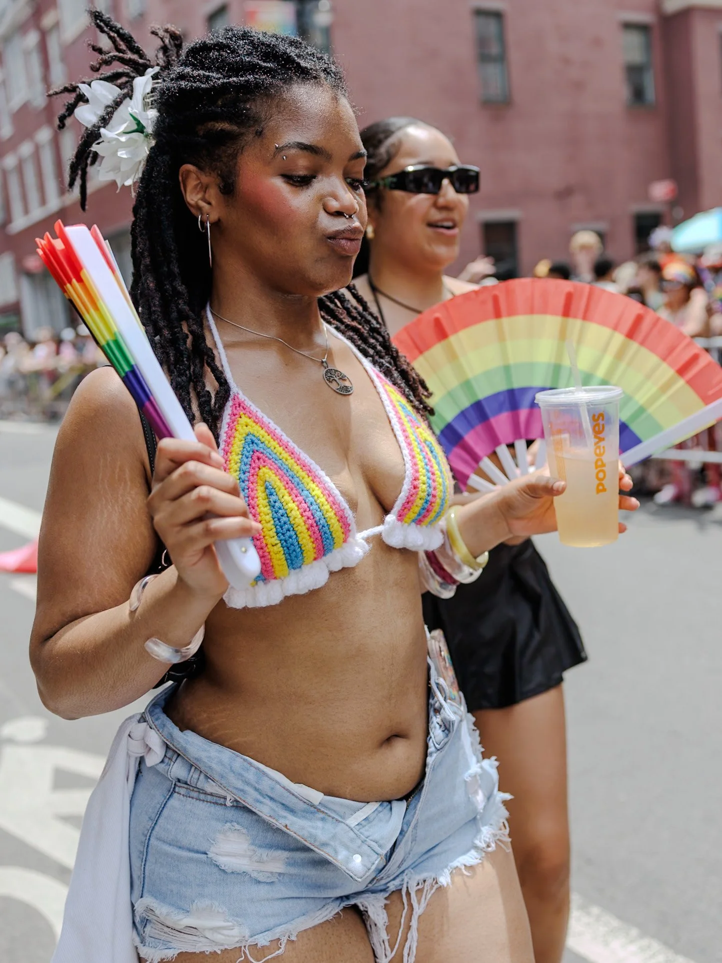Woman with braids holding a rainbow fan in the crowd