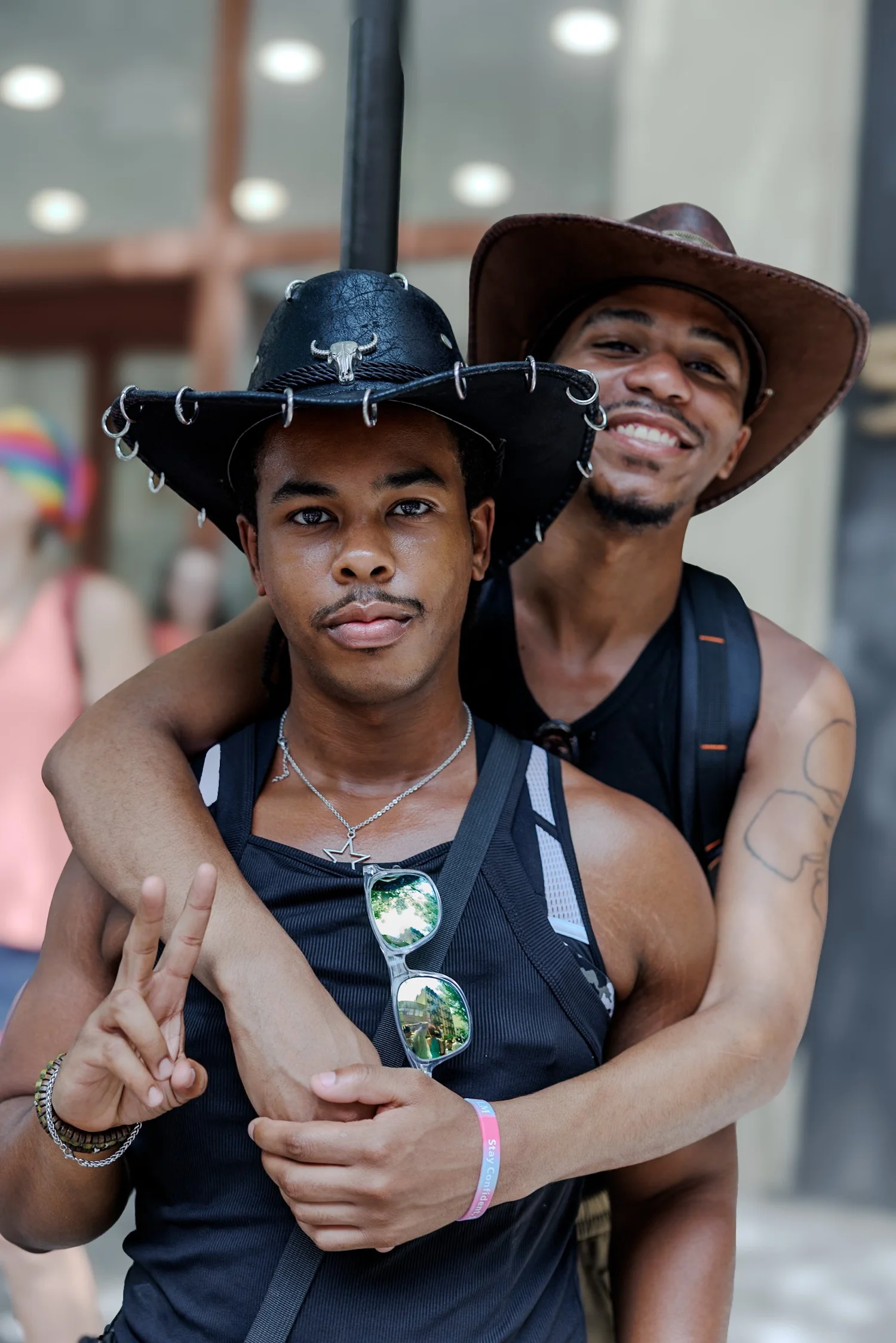 Two men in cowboy hats embracing on a crowded street