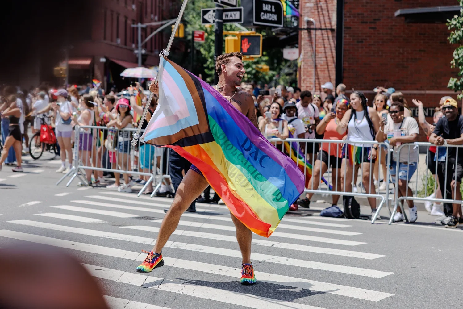 Marcher dancing across the street with a large rainbow flag