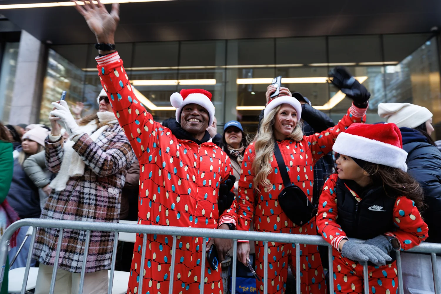 Spectators in Santa hats cheering behind barricades