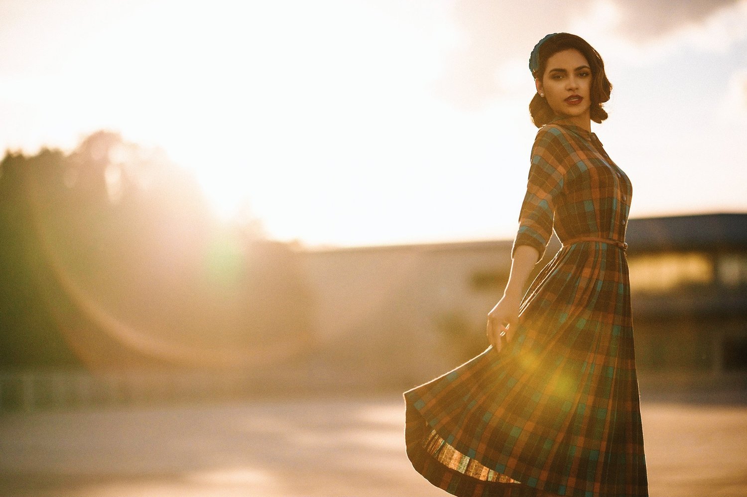 Woman in a plaid coat walking into a low sun