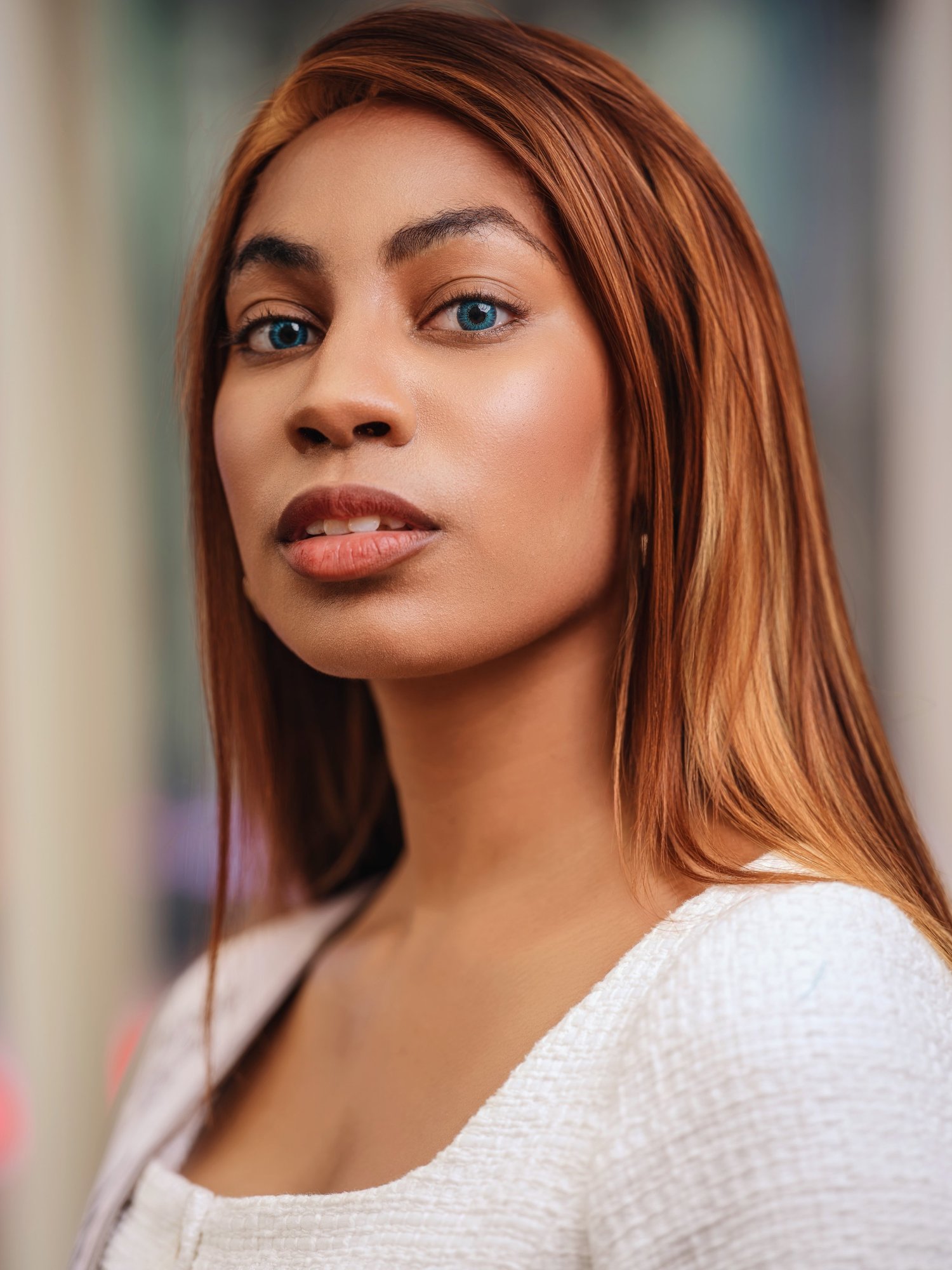 Woman with long auburn hair in a white top, softly lit