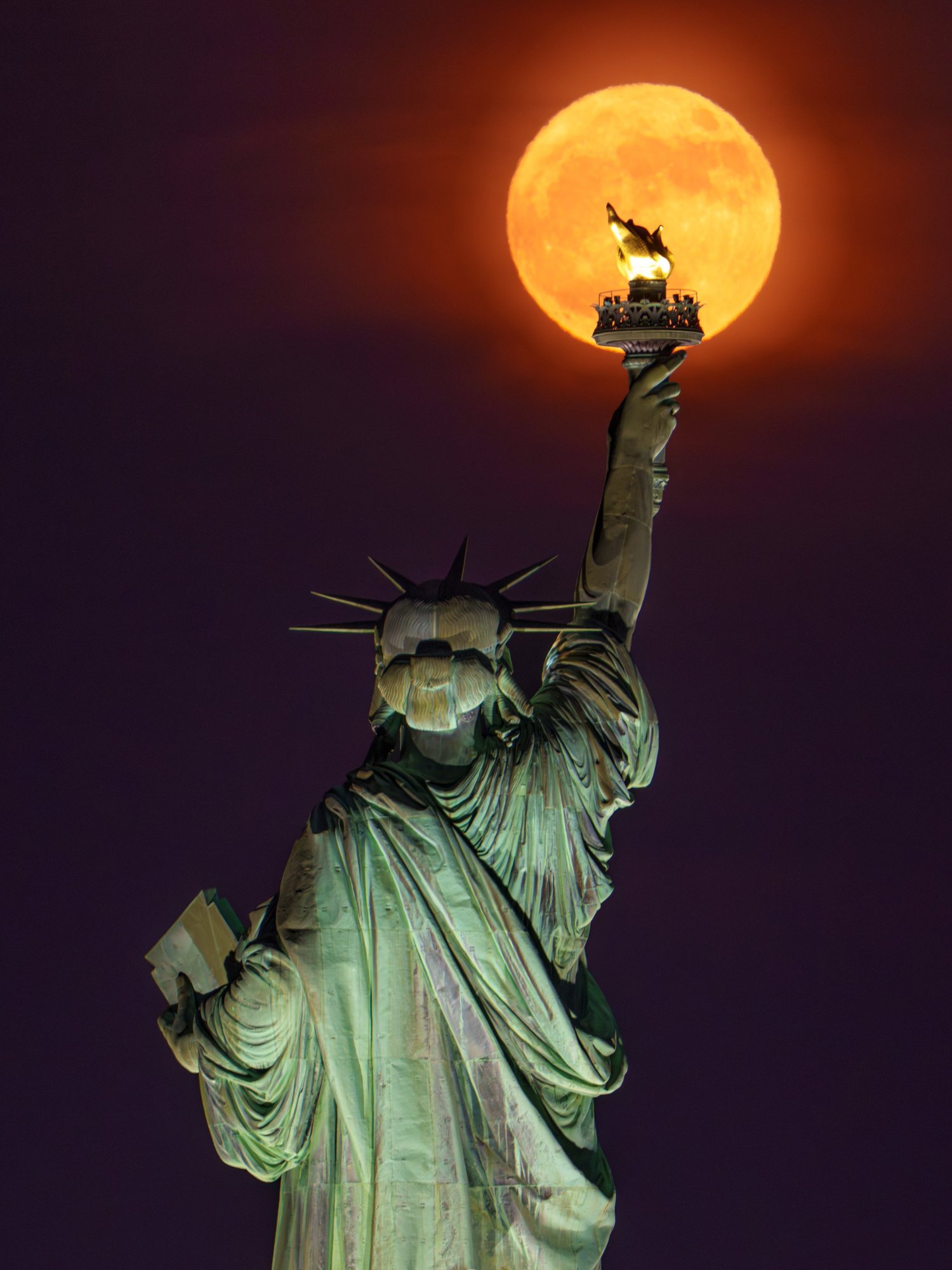 The Statue of Liberty beneath a full moon