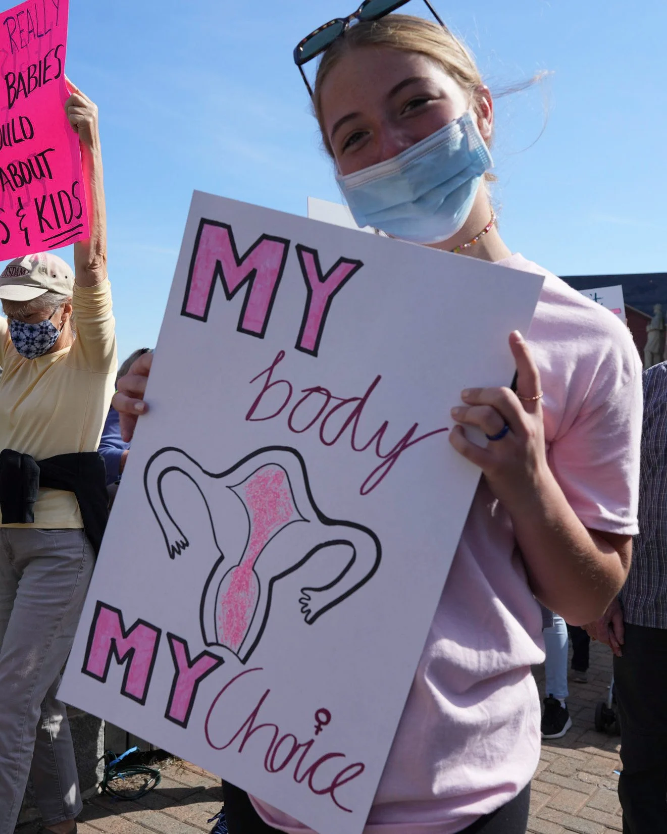 Masked protester holding a sign reading “My body, my choice”