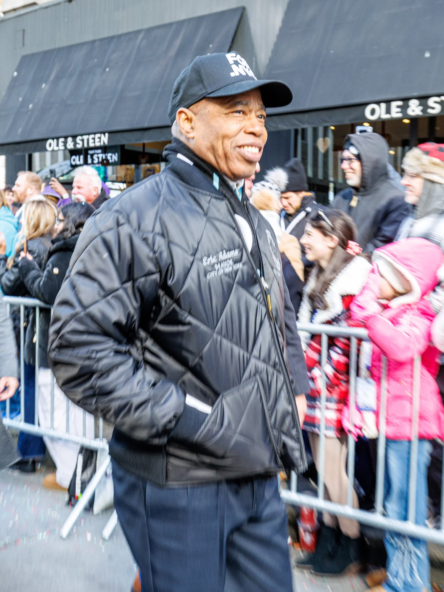 Man in a black jacket and cap walking the parade route