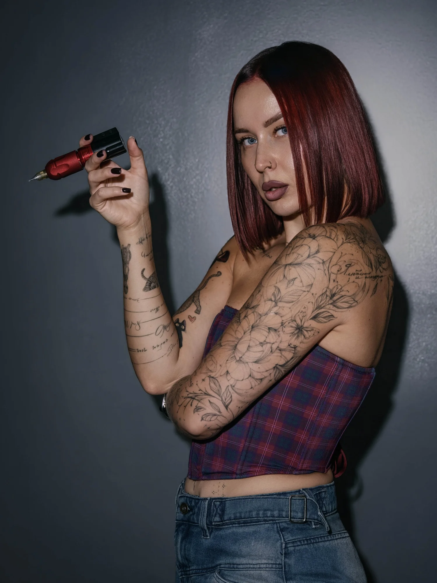 Tattooed woman with red hair against a gray wall