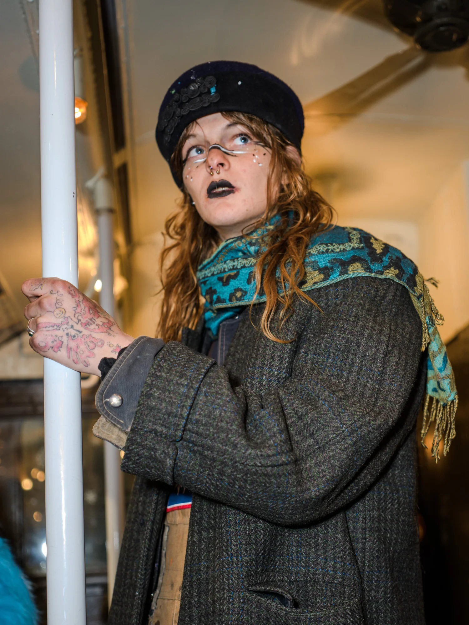 Woman in a vintage hat, glasses and scarf holding a pole on a vintage subway car