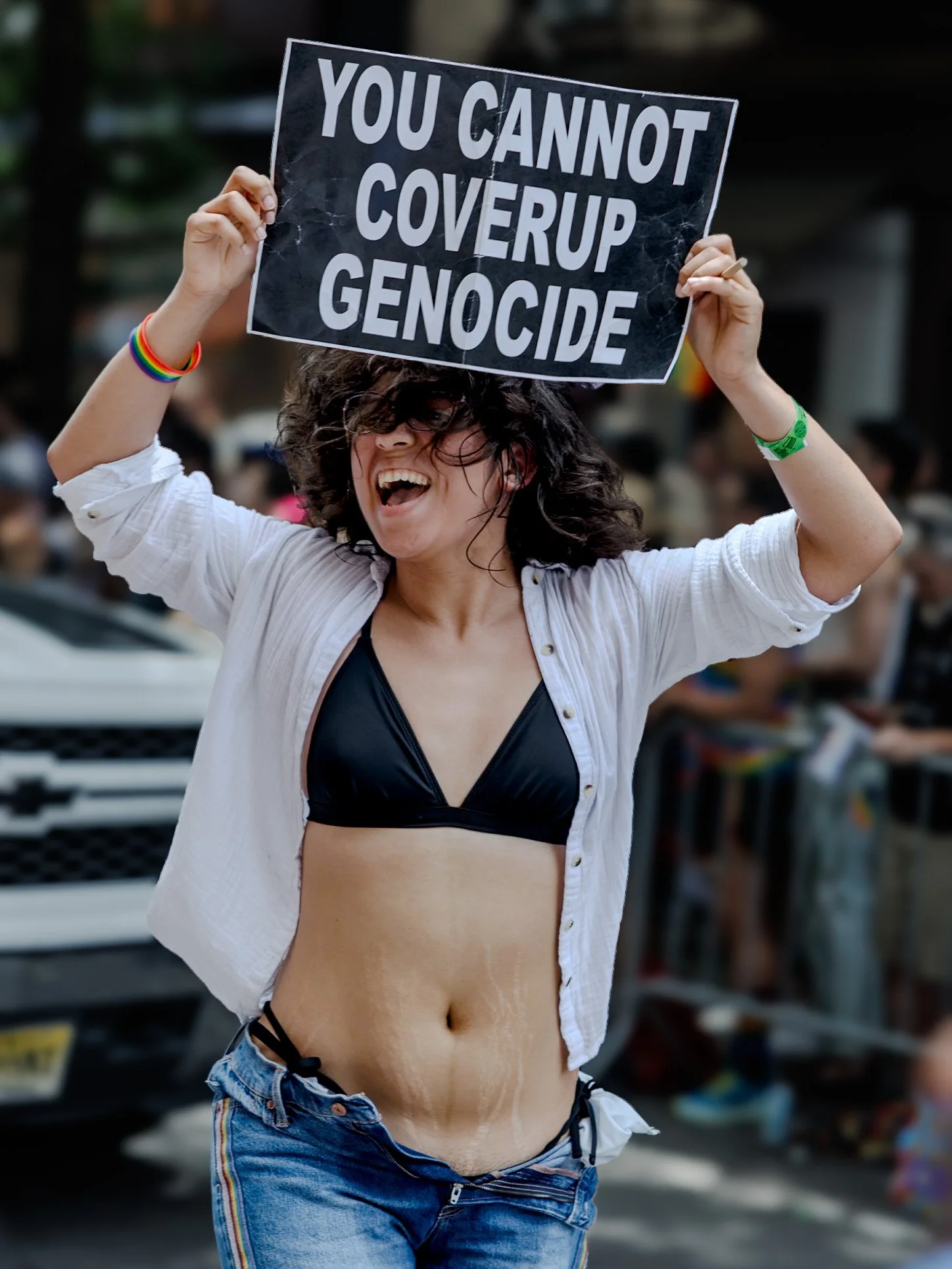 Marcher in sunglasses holding up a hand-lettered sign reading “You cannot coverup genocide”