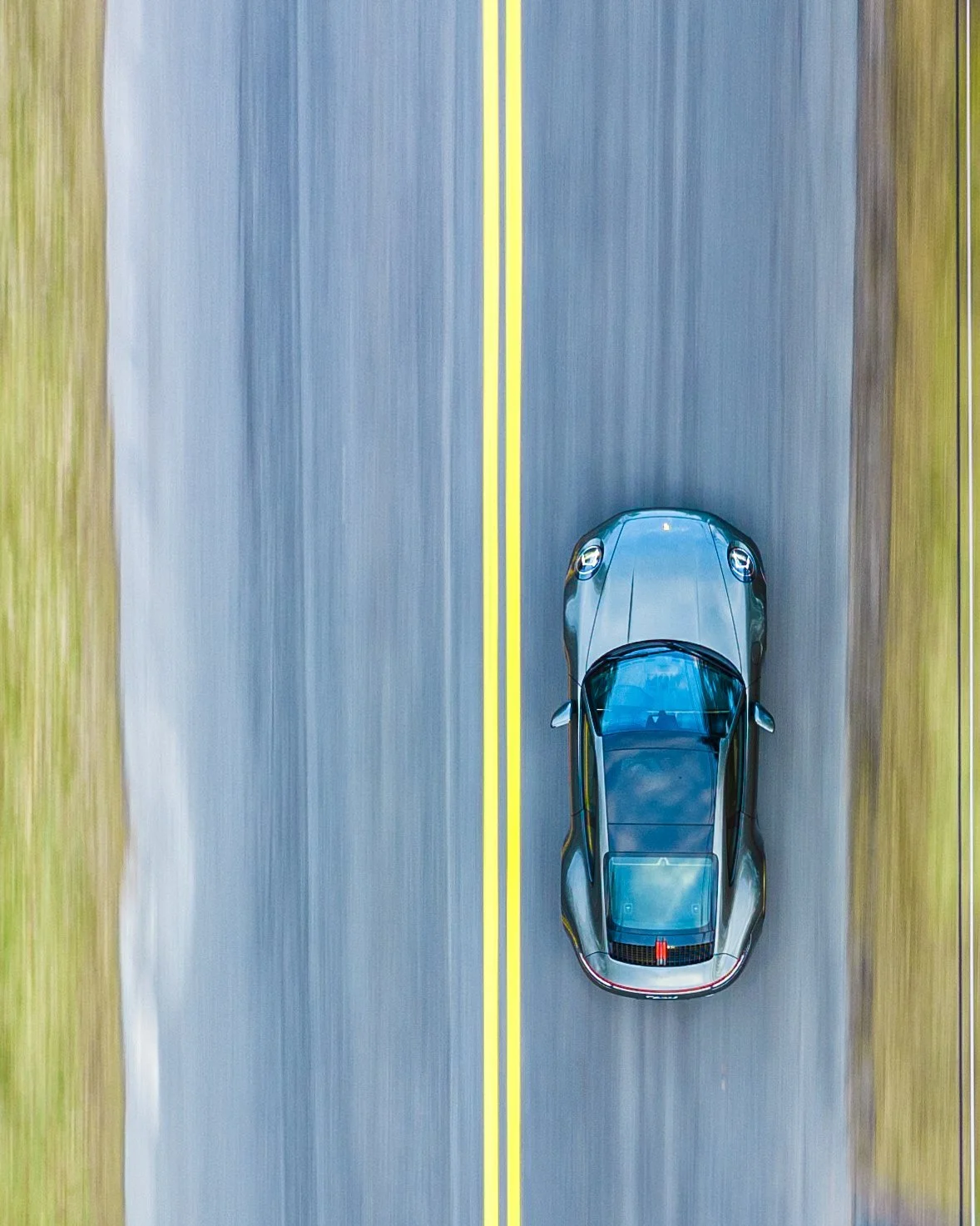 Overhead view of a blue sports car on an empty road