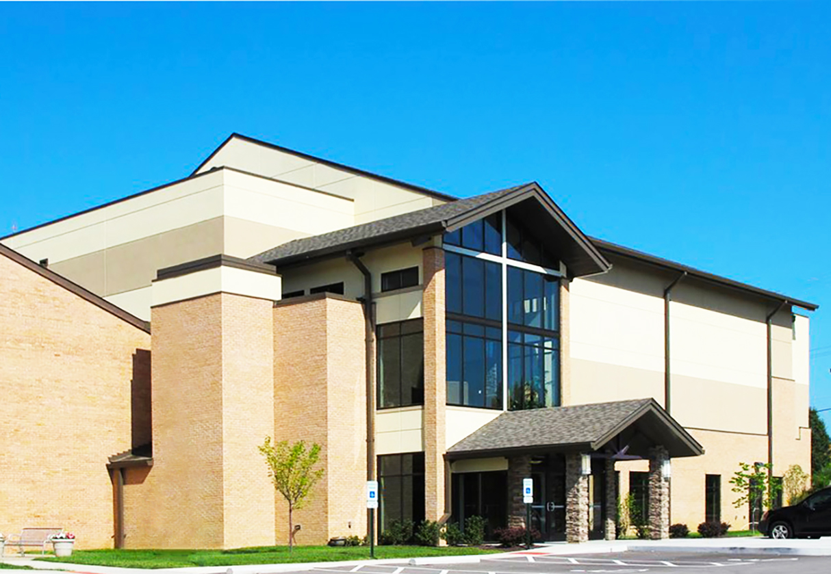 Modern church building with large windows and brick exterior under a clear blue sky.