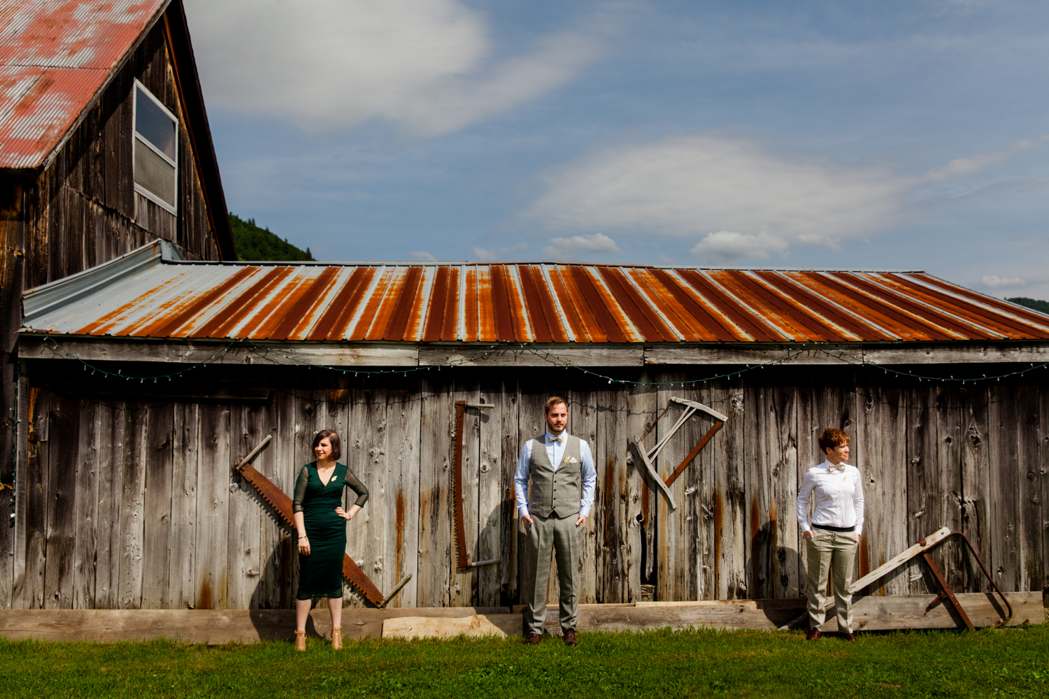  A groom and his grooms women stand in front of a barn in upstate, NY. 
