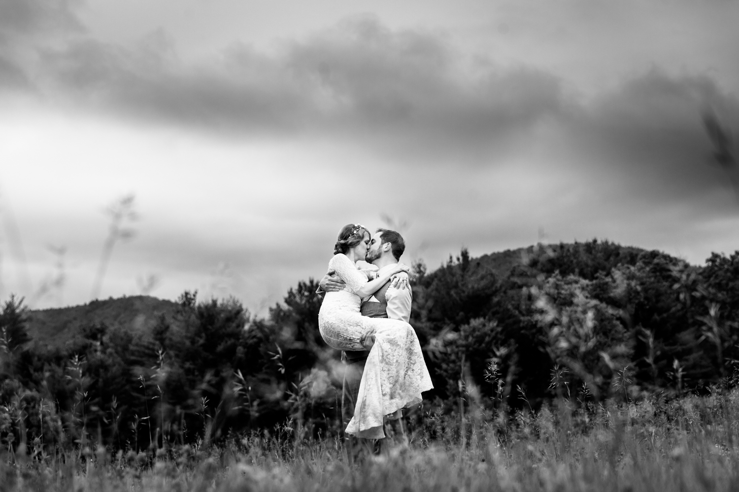  A groom carries a bride in a field 