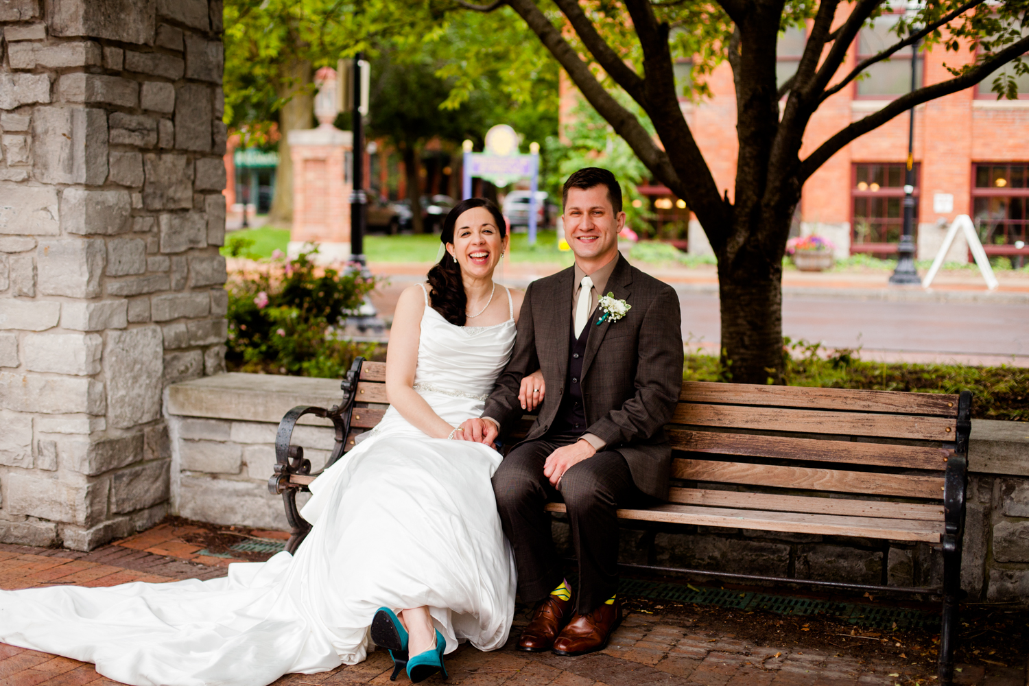  Bride and groom sit on bench laughing 