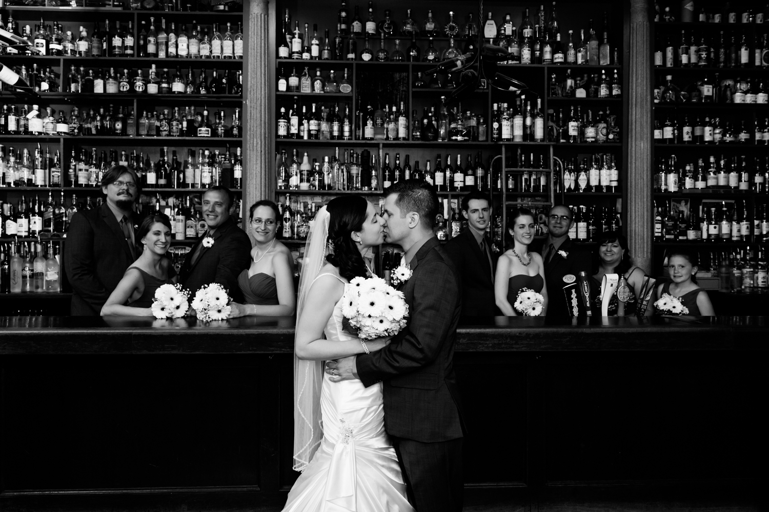  Bride and groom kiss in front of the bar at Al's Wine and Whiskey Lounge in downtown Syracuse, NY 