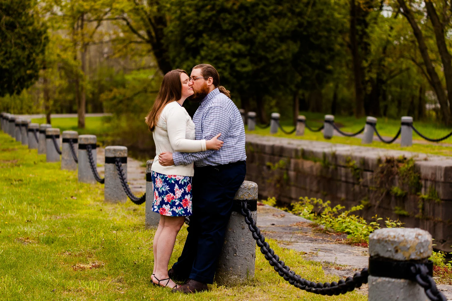 Man and woman leaning up against small fence in Syracuse, NY during a springtime engagement shoot.