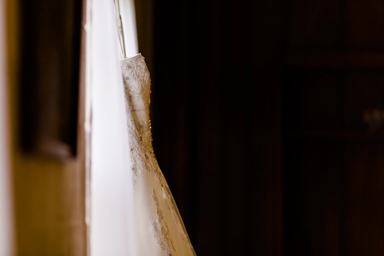 Wedding dress hangs in a window.