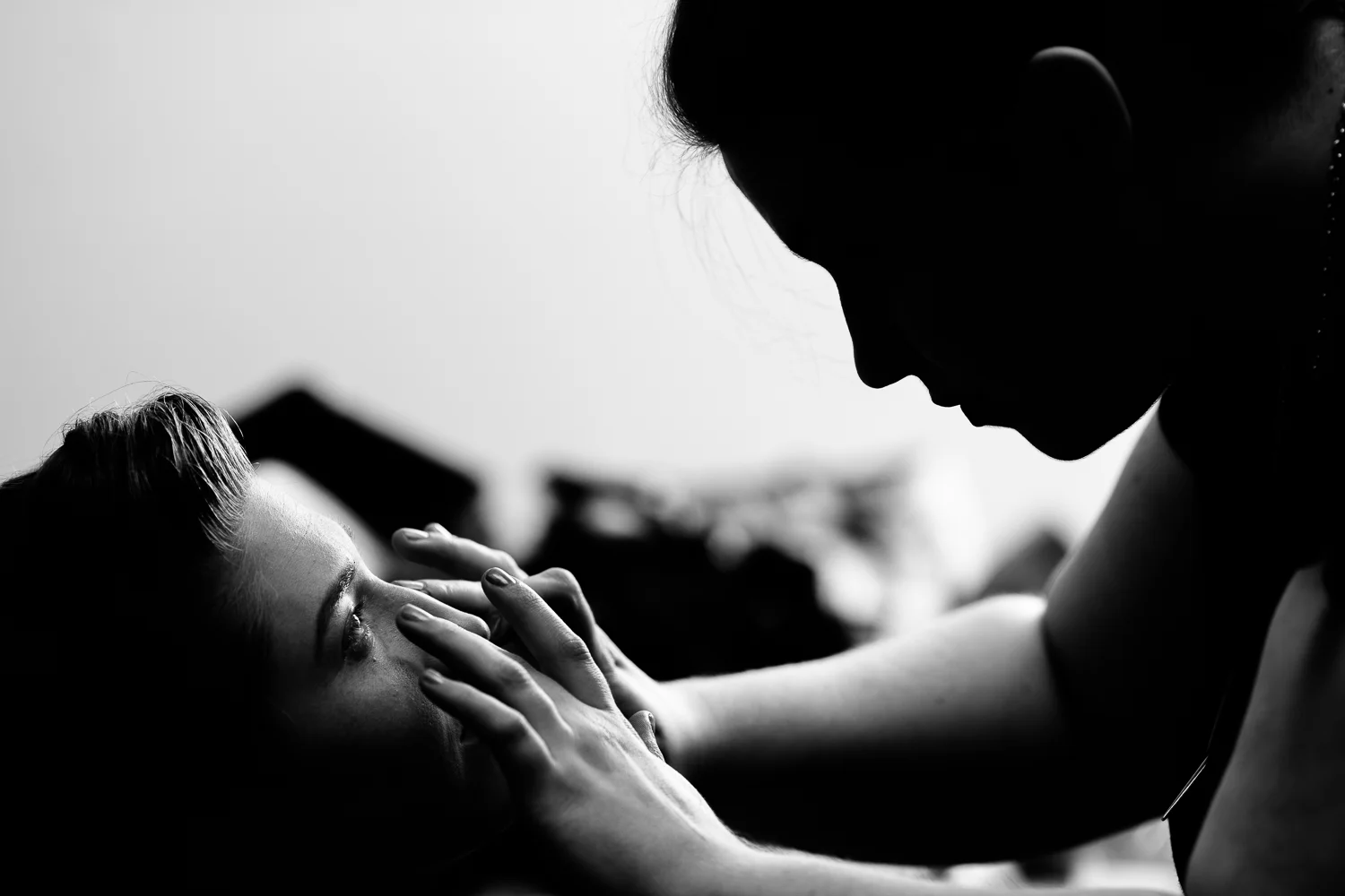 Black and white image of bride's eyes as a makeup artist applies makeup. 