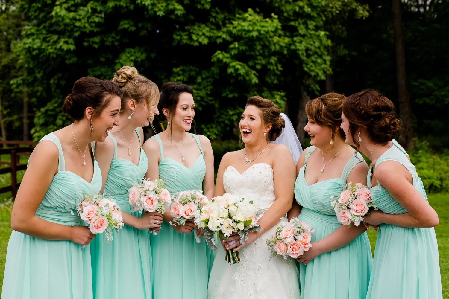 Bridesmaids stand together in light blue dresses laughing.