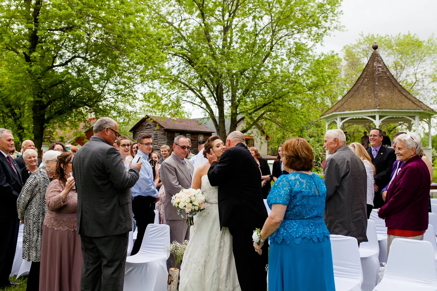 Father kisses bride on the cheek at the end of the aisle.