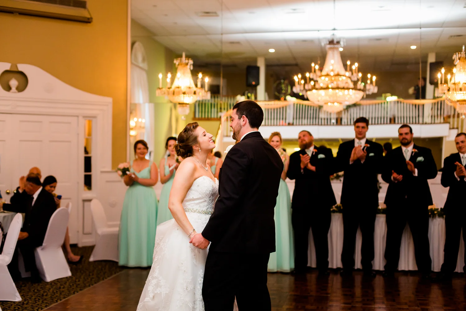 Bride and groom have first dance. Bride smiles at groom.