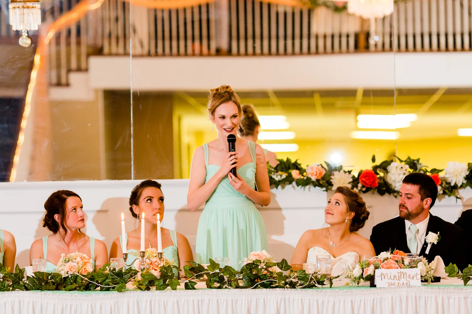 The maid of honor gives a speech. The bride looks up at her.