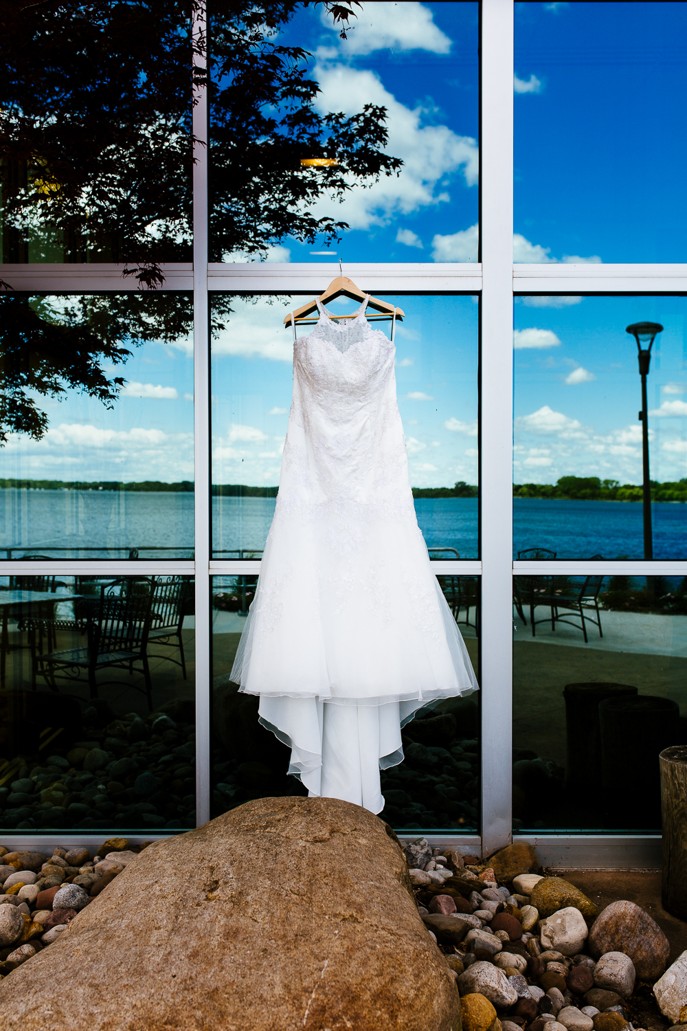  White wedding gown hanging on reflective windows. 