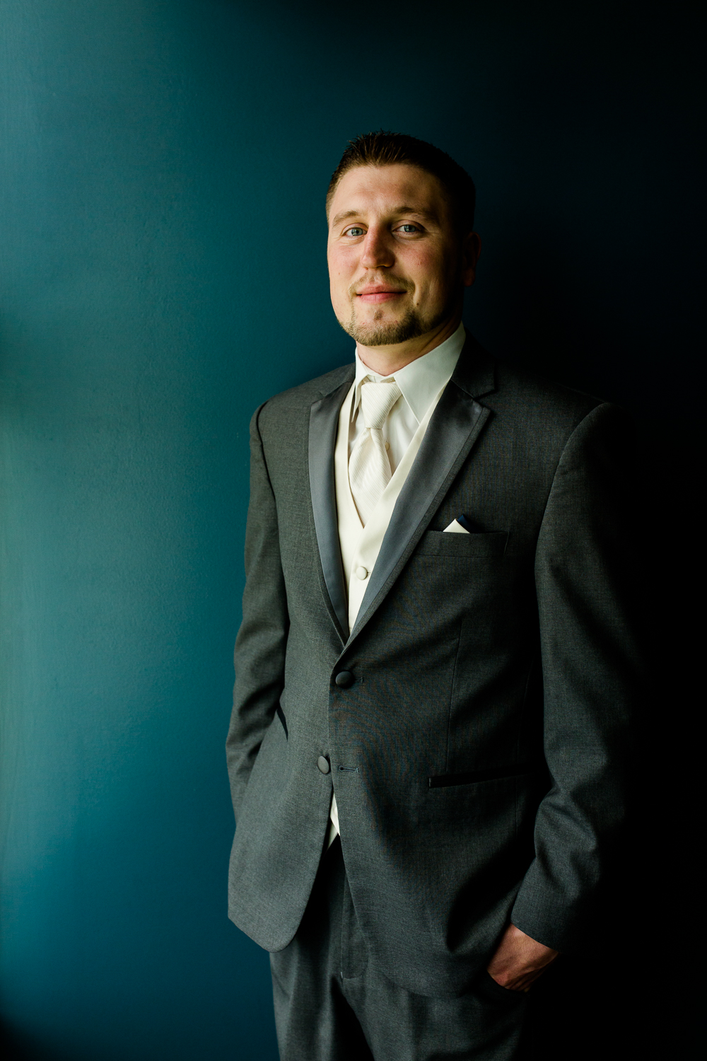  Portrait of a groom against a blue background. He is looking at the camera. 