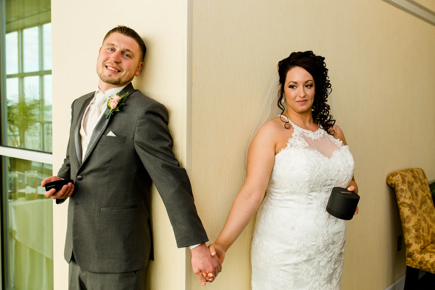 Bride and groom hold hands around a corner exchanging gifts.