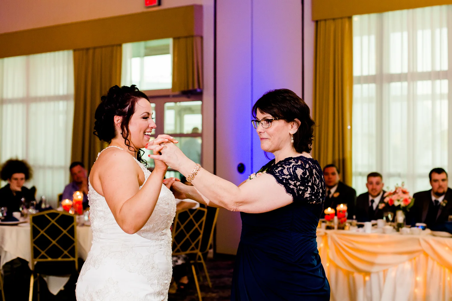 Bride laughs while dancing with her mother.
