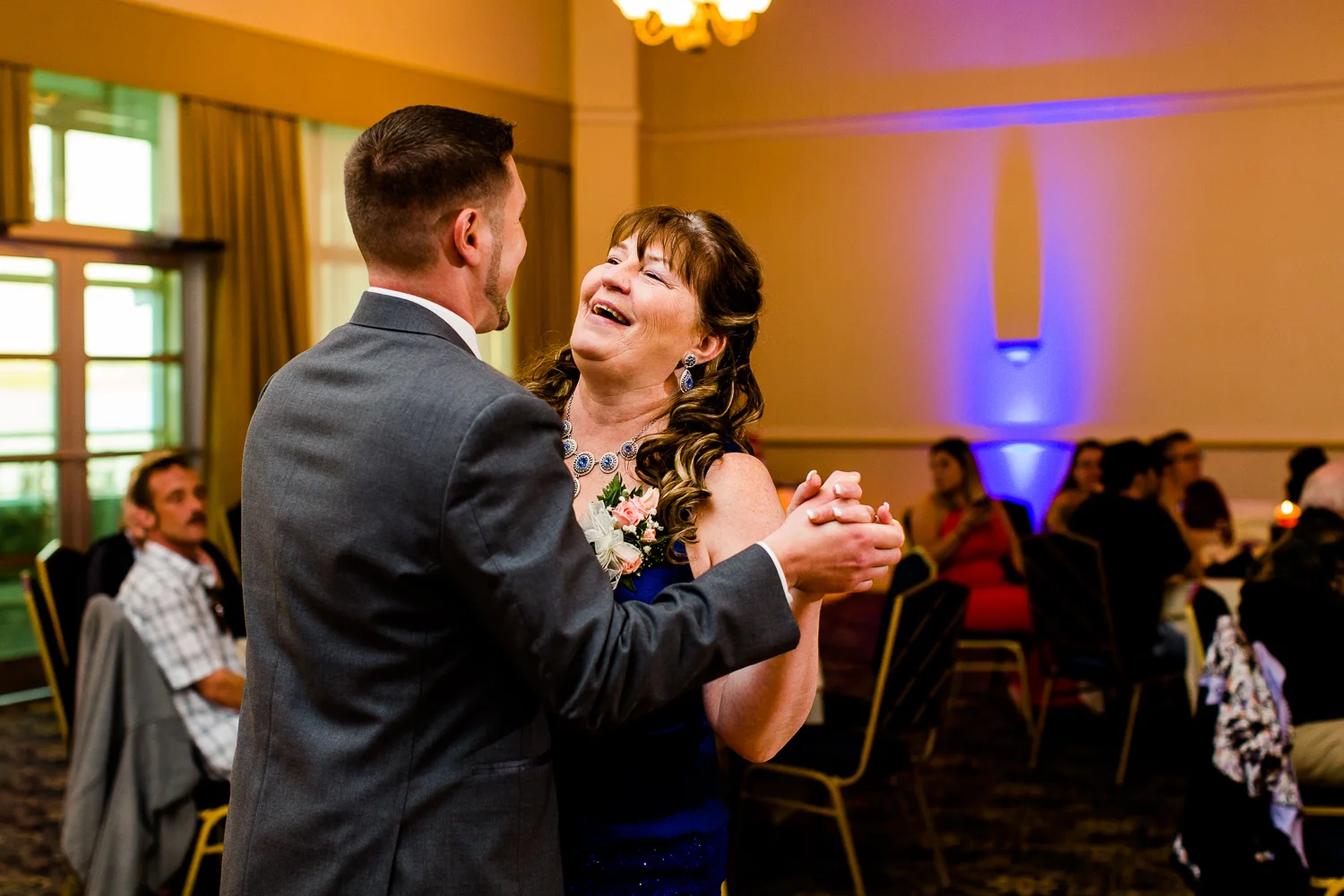 Mother son dance. The mother is laughing while dancing with the groom.