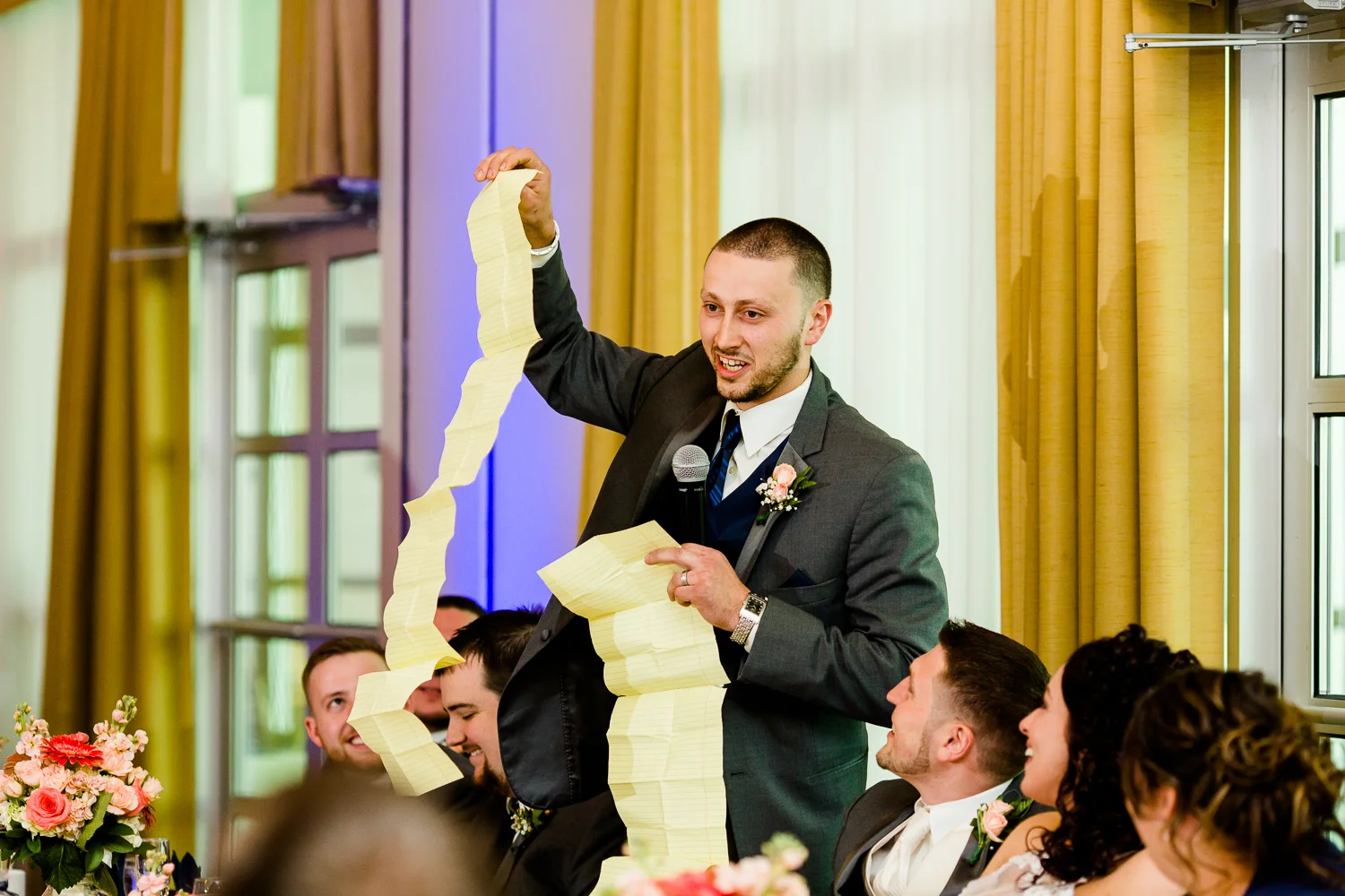 The best man holds up a giant speech as a joke.