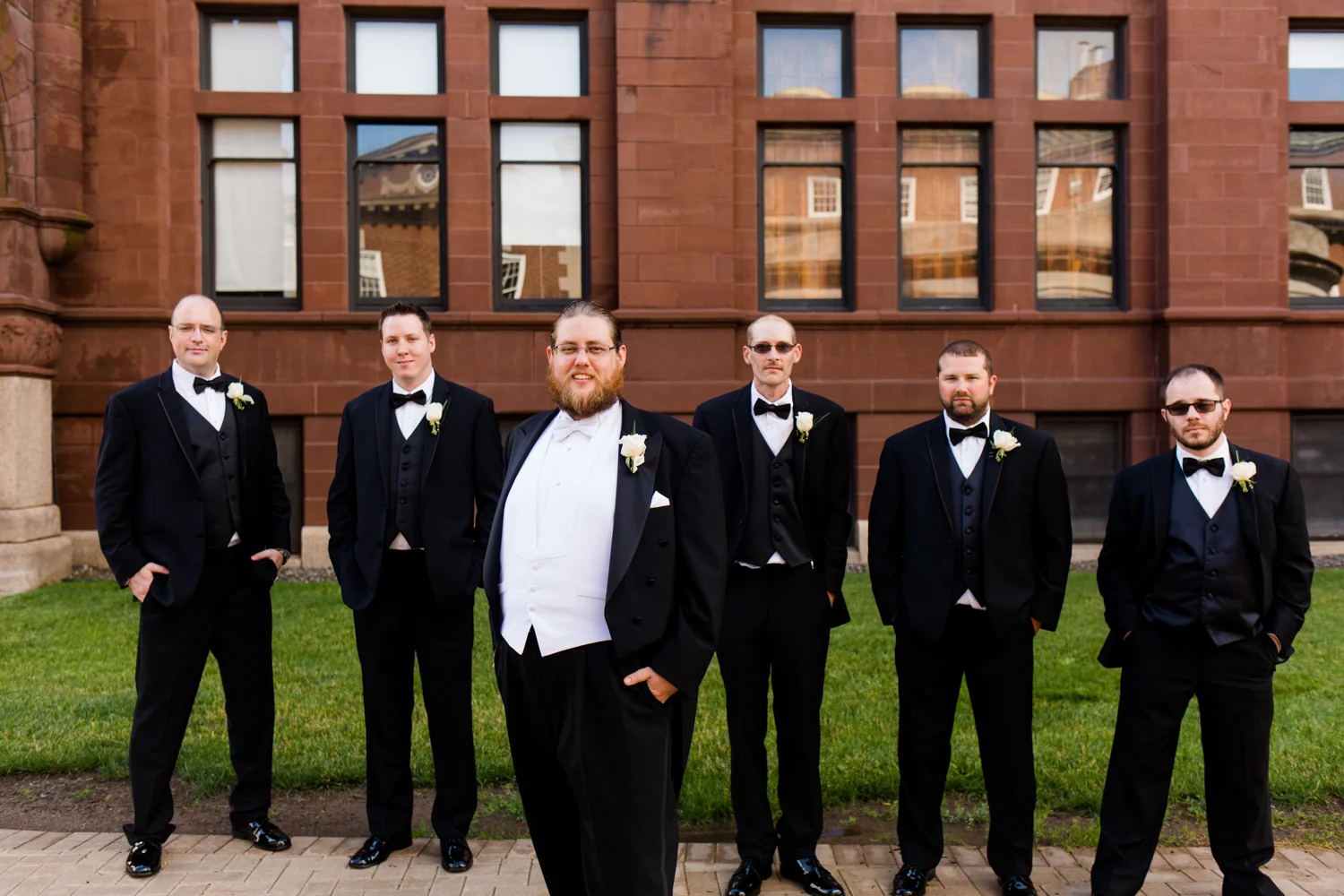 Groom in a tux with his groomsmen behind him.