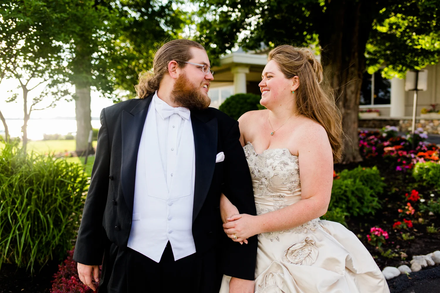 Portrait of bride and groom looking at each other. There are flowers in the background.