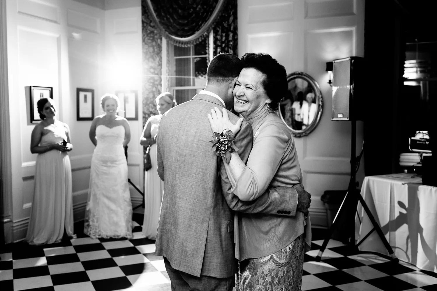 Black and white image of mother smiling during mother son dance at a wedding.
