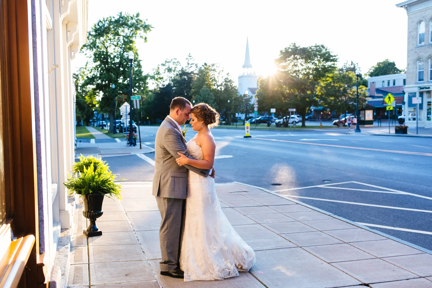 Bride and groom stand on the street corner at sunset in Cazenovia, NY.