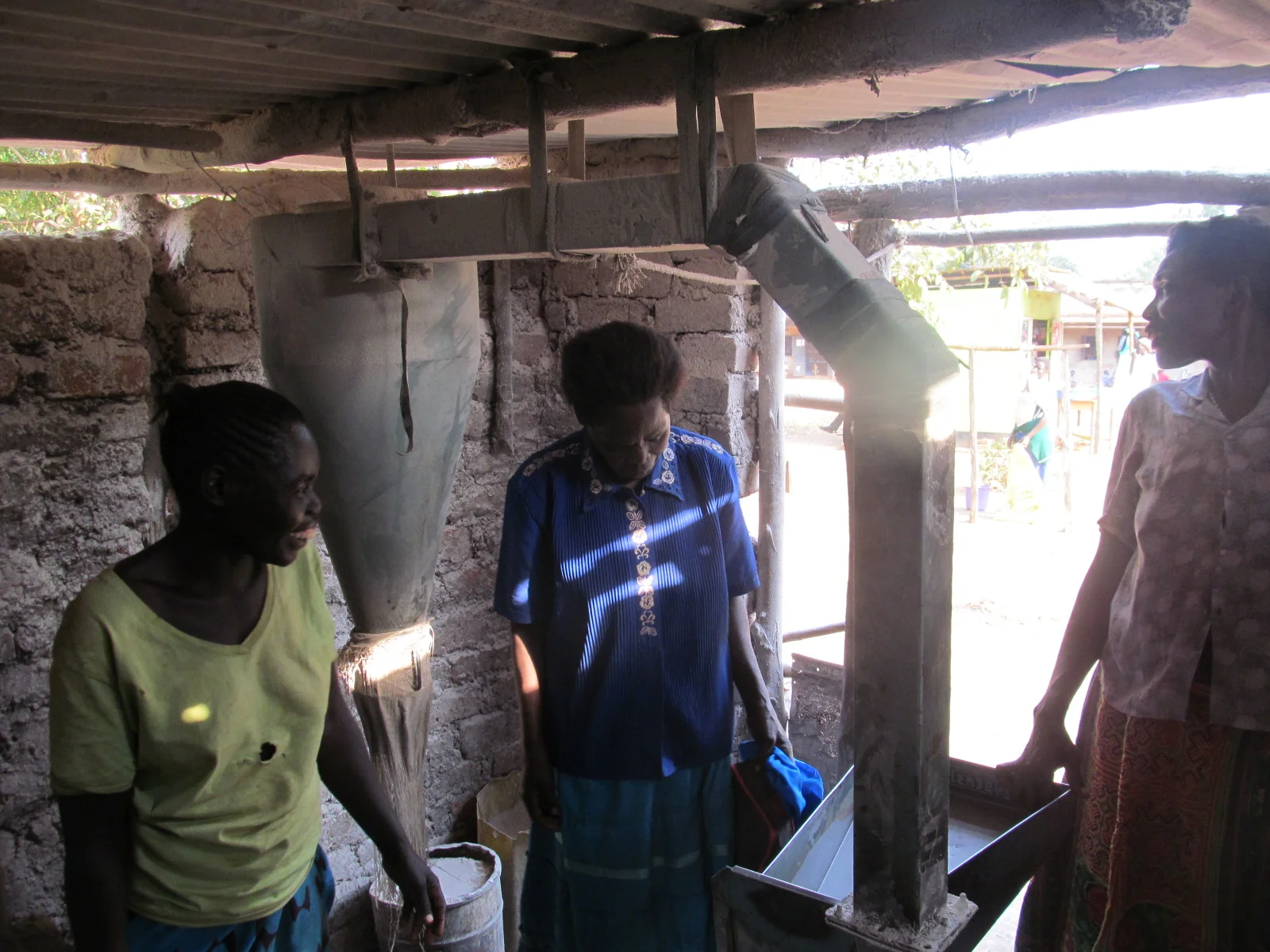 Three group members working the corn grinding mill, they are so happy for this opportunity!