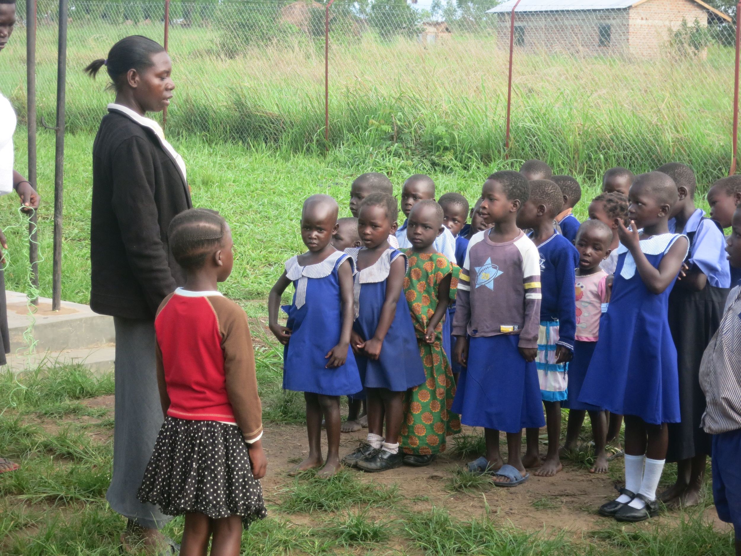The Head Teacher calls the leader to the front for prayer before entering the classrooms. &nbsp;