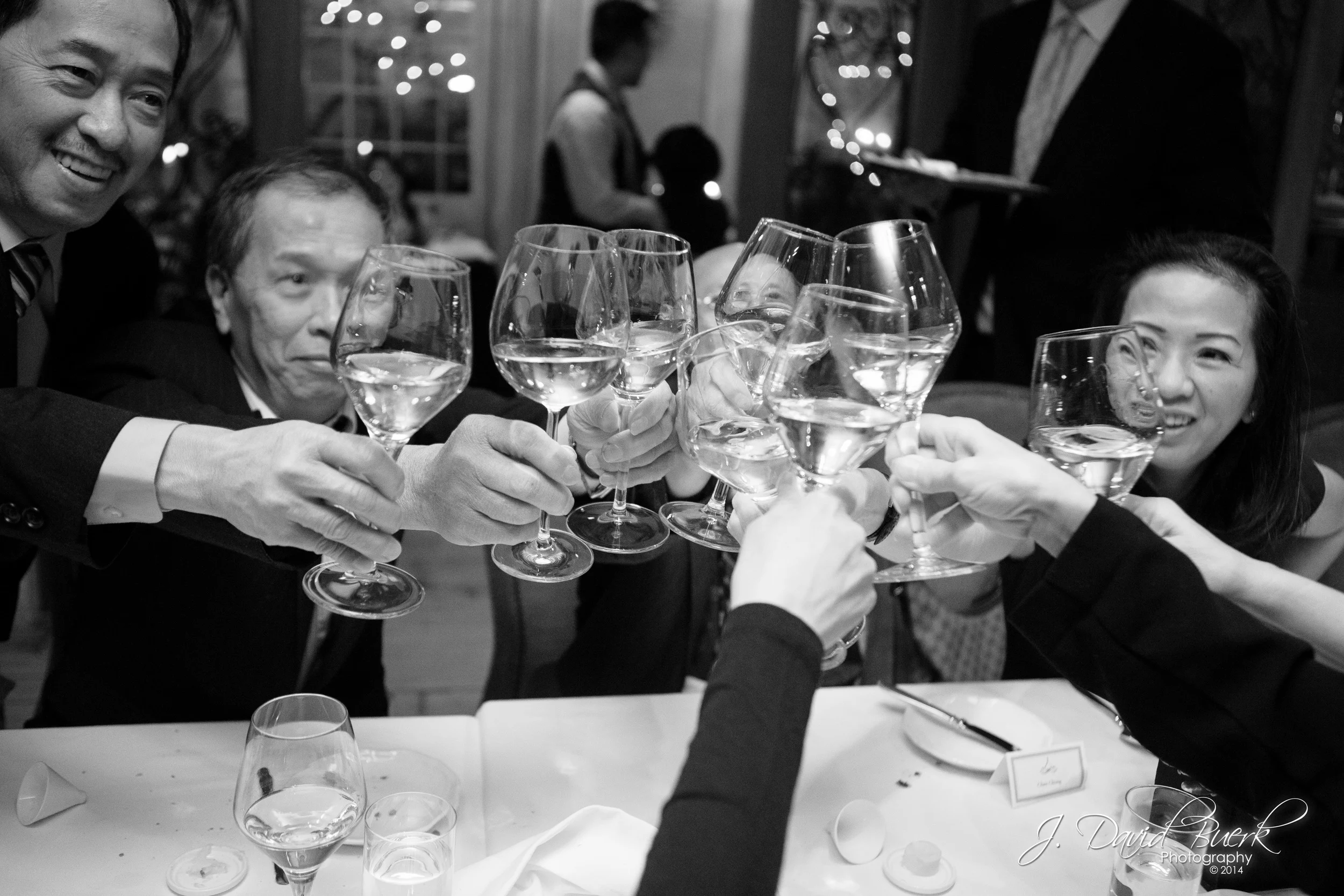 Glasses clink in celebration of a wedding reception toast.