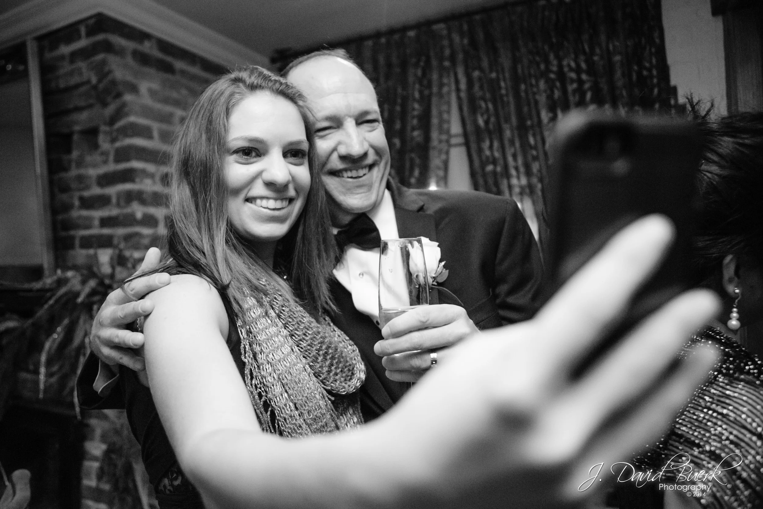 A groom takes a selfie with a wedding guest. "Selfie" was 2014's Word of the Year.