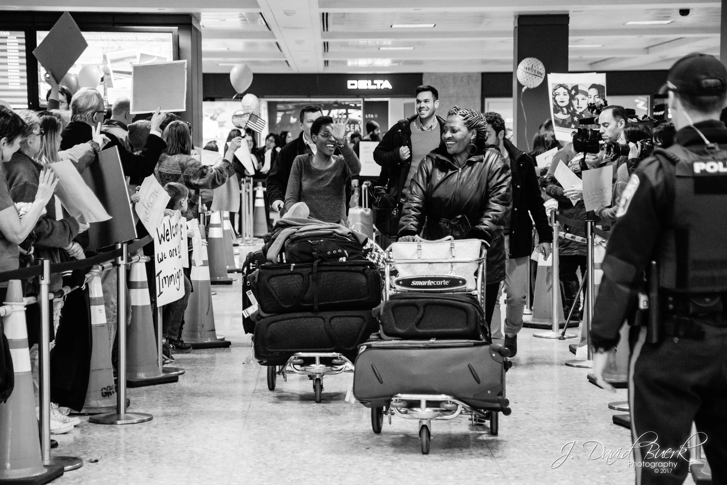 Internationally arriving passengers exit the International Arrivals Building to a sea of cheering protestors welcoming their arrival after clearing customs.