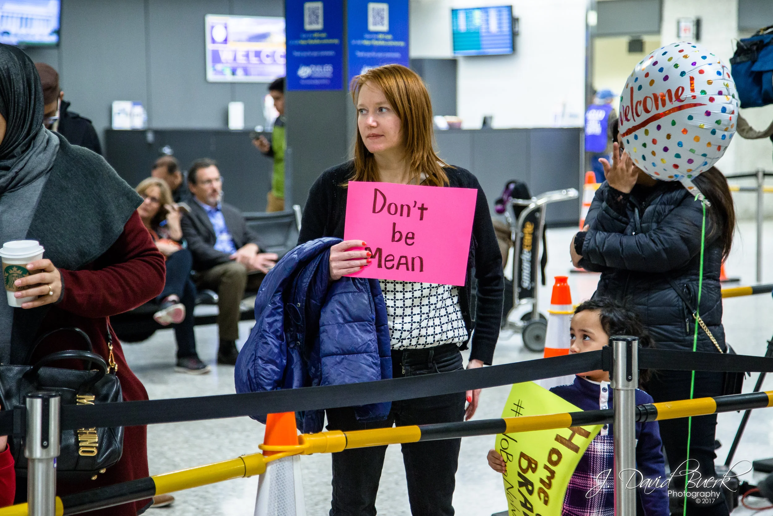 A woman holds a sign that simply reads, "Don't be Mean."