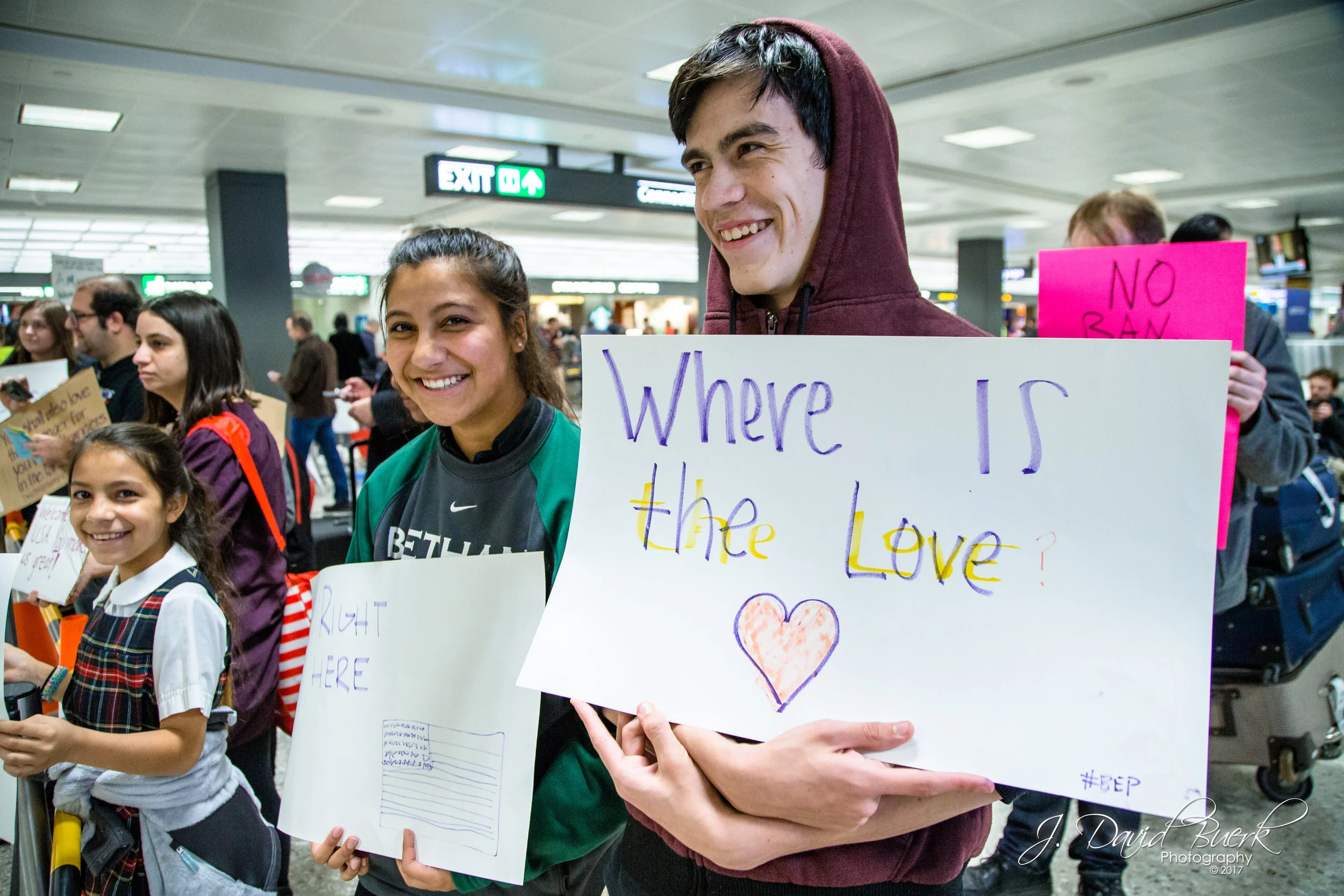 Protestors who came together hold signs which complement one another's messages.