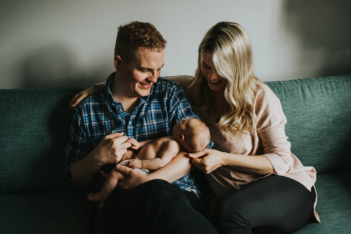 Father and mother holding baby daughter on couch