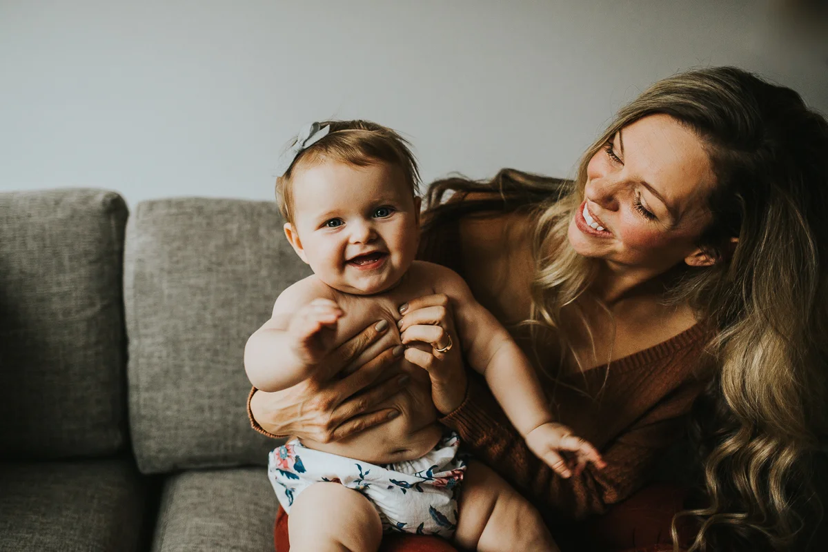 Mother and daughter smiling in the couch intimate at home family photos