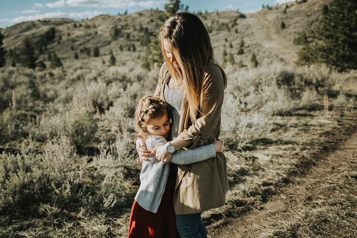 Mother and daughter hugging in sagebrush field Kamloops