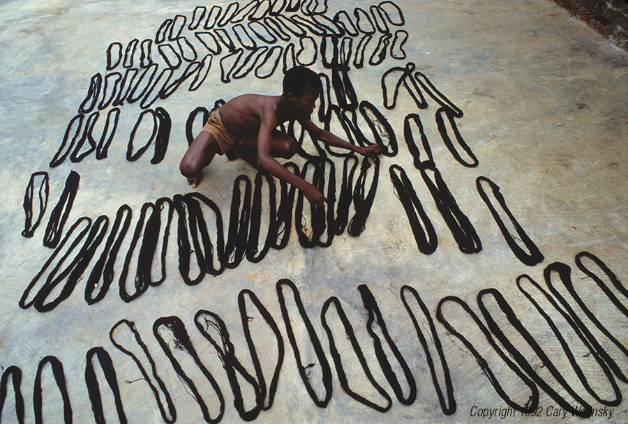 A boy lays out freshly dyed cotton tread to dry in the village of Bonwire in Ghana, Africa. Bonwire is a village where kente cloth is woven. 